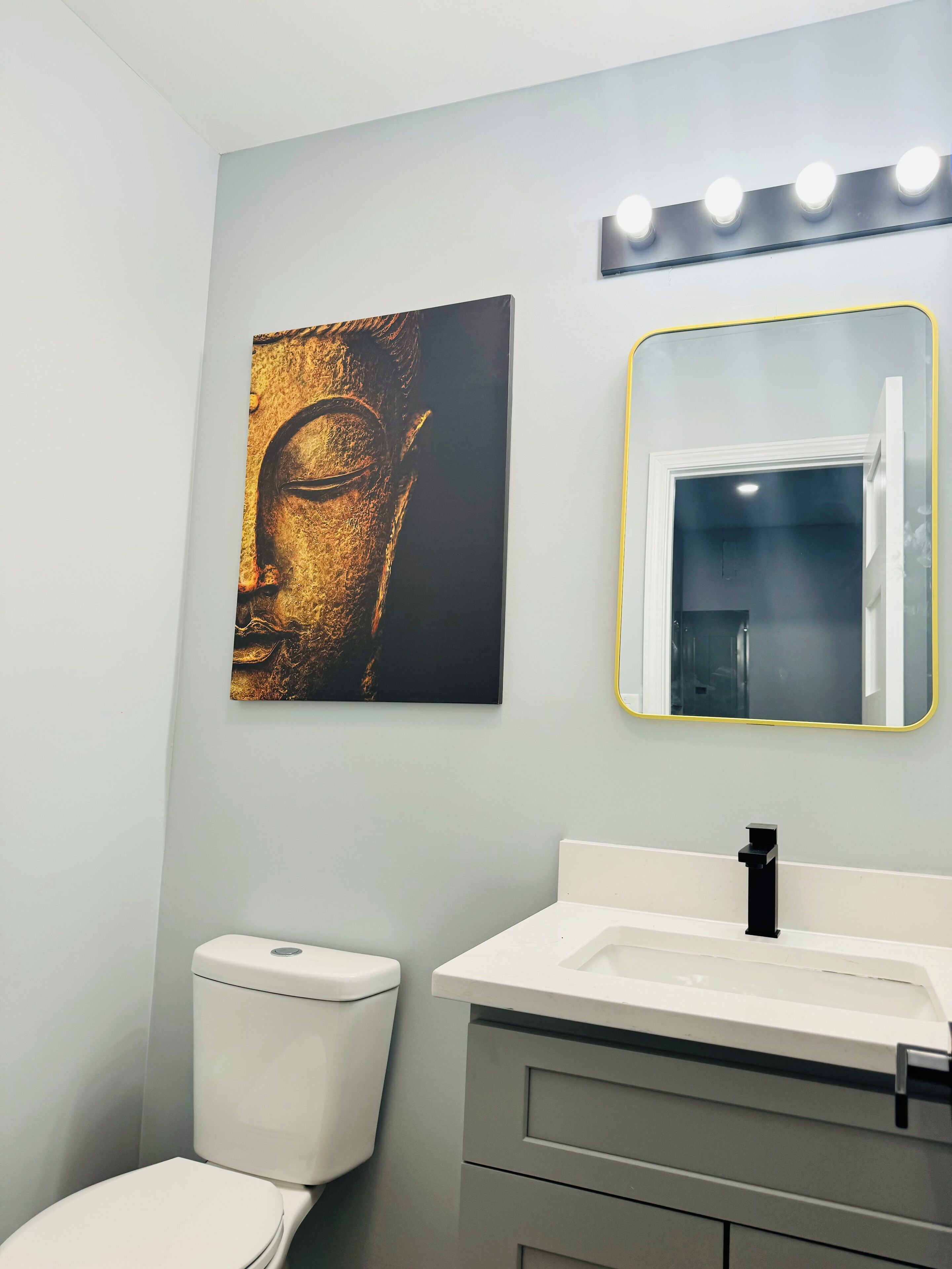 Une salle de bain comprenant des toilettes, un lavabo et un miroir fixé au mur, avec éclairage intégré.