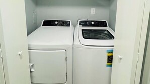 A laundry room with two stacked washers and dryers, a white door, and a light blue wall.