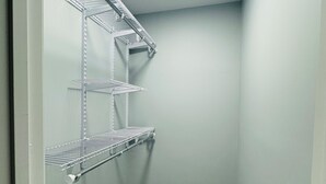 A narrow hallway with a wooden floor and metal shelving units against the wall.