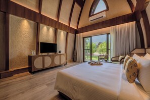 A spacious bedroom with a large bed, a TV, and a wooden cabinet.