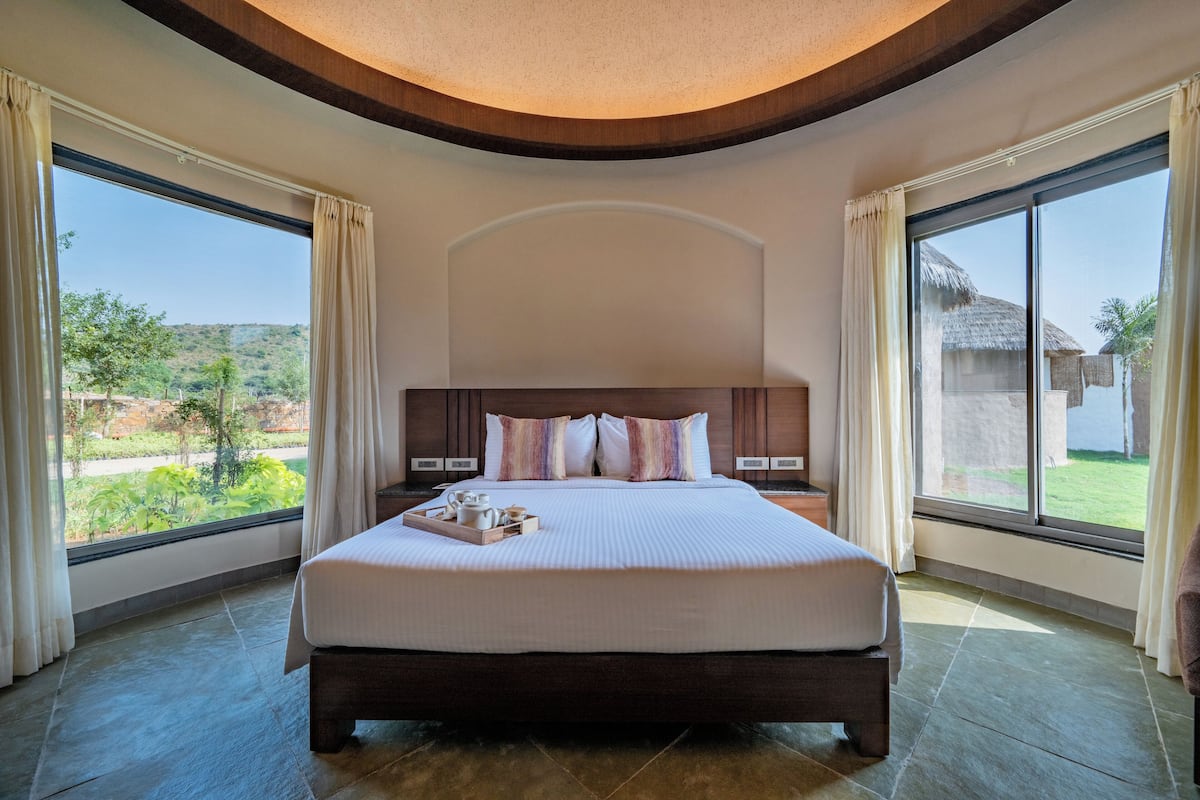 A large bed with a wooden headboard, two bedside tables, and a tray with items on the bed.