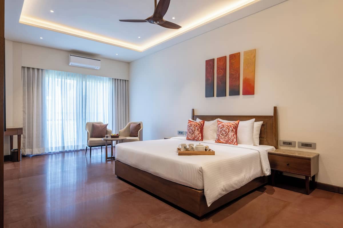 A hotel room with a large bed, a desk, a chair, and a ceiling fan.