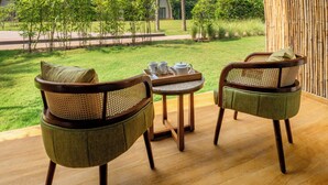 A terrace with two wicker chairs and a small table, overlooking a lush garden and a distant mountain range. - Ananta Spa & Resort Ajabgarh (Thanagazi)