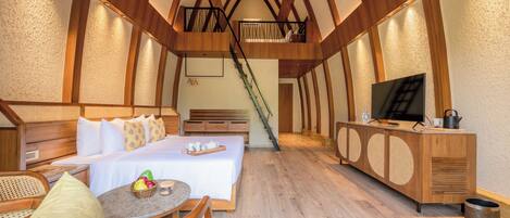 Ein geräumiges Schlafzimmer mit einem großen Bett, einer Sitzecke mit Tisch und Stühlen, einem Fernseher und einem Holzschrank.