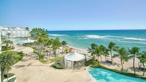 Un resort con playa, palmeras, piscina y vista al océano.