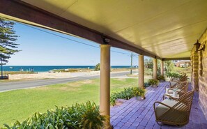A covered outdoor seating area with wicker chairs and a view of the sea. - Tranquil water views from your private front deck (Shoalwater)