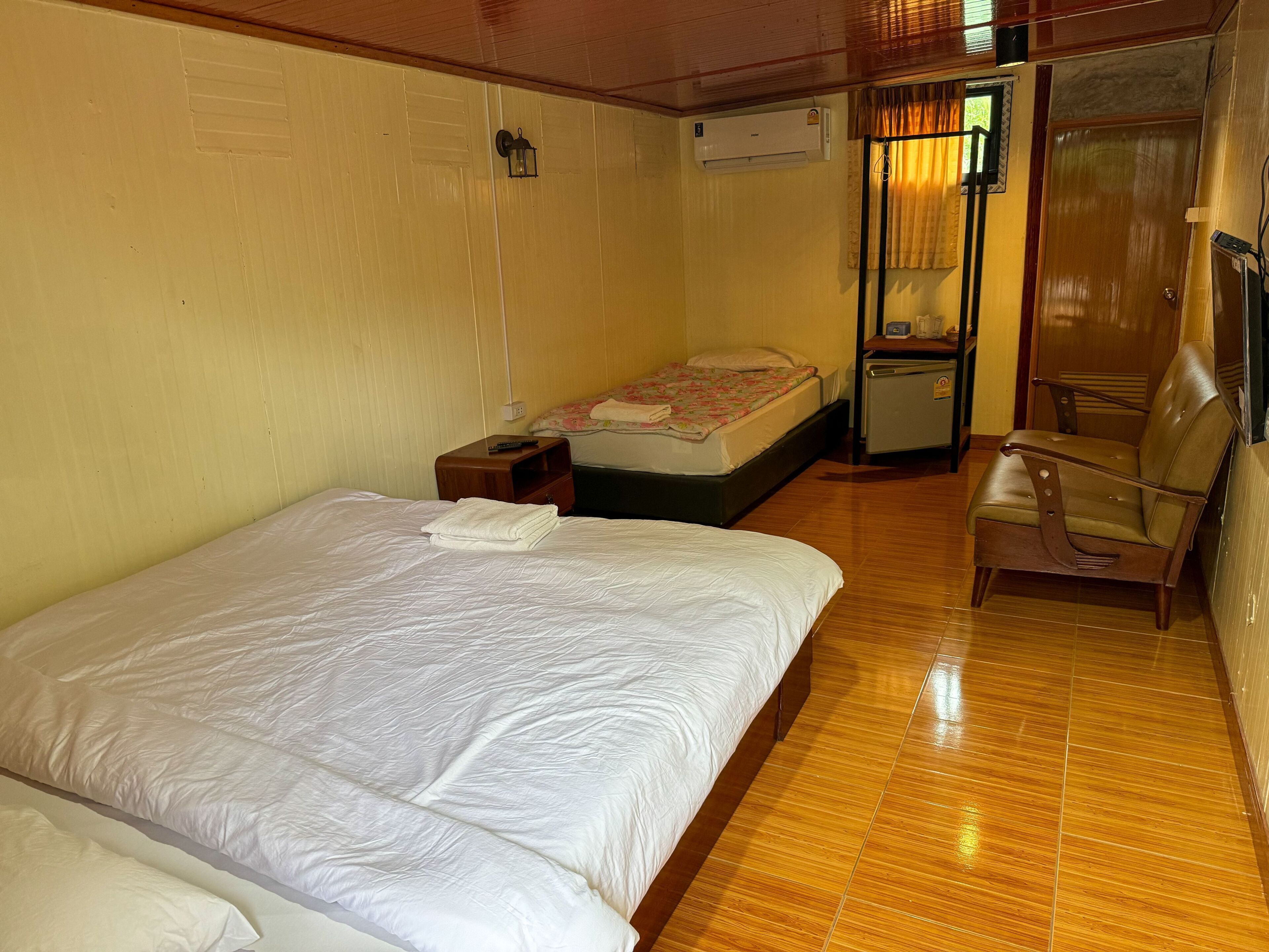 A hotel room with a bed, a small desk, a chair, a wardrobe, and a window with curtains.