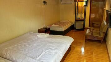 A hotel room with a bed, a small desk, a chair, a wardrobe, and a window with curtains.