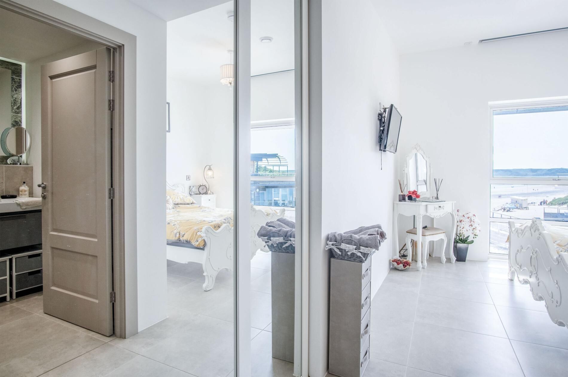 Un dormitorio moderno con un ventanal grande, una mesita de noche, un espejo y vistas a la ciudad.