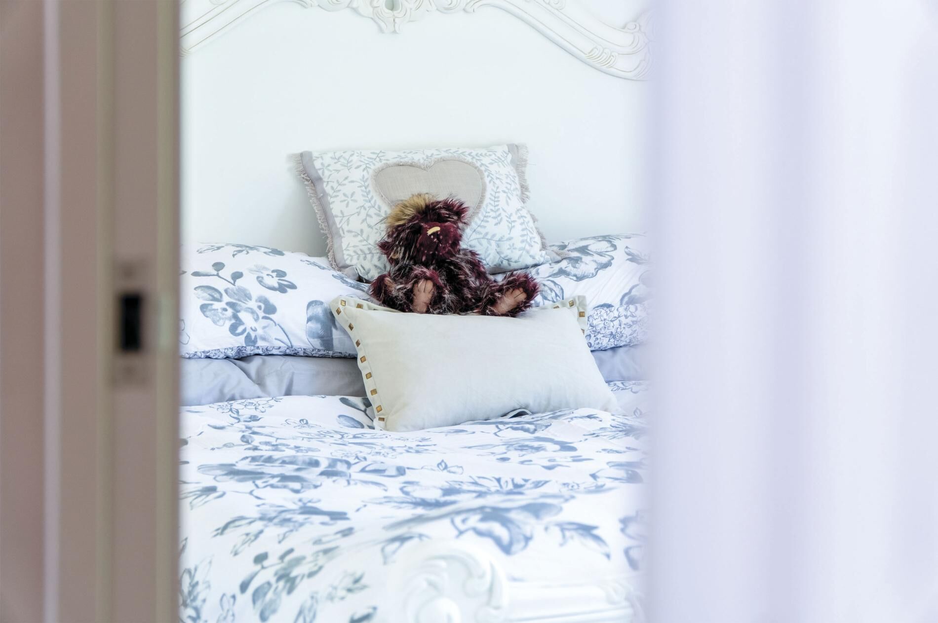 Een slaapkamer met een bed belegd met bloemenprint beddengoed, een decoratief hoofdeinde en een zacht kussen.