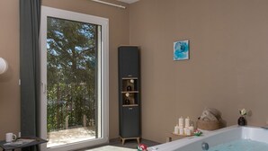 Ein modernes Badezimmer mit Badewanne, Duschbereich und einem Fenster mit Blick auf Bäume.
