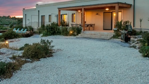 Ein modernes Haus mit überdachter Terrasse, Sitzgelegenheiten im Freien und Grillplatz.