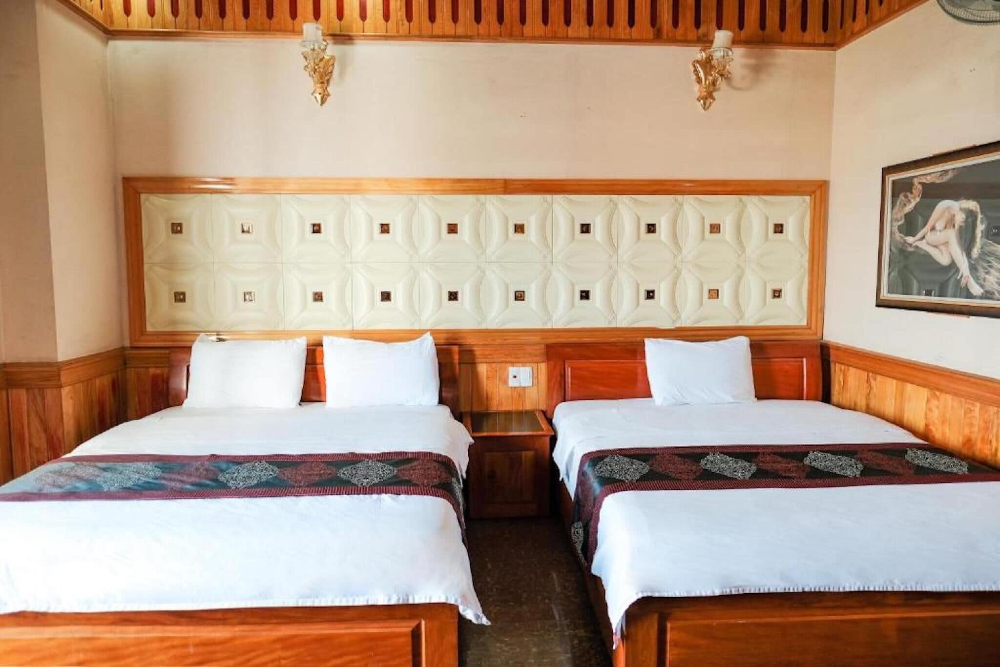 A hotel room with two beds, wooden headboards, and a decorative ceiling panel.