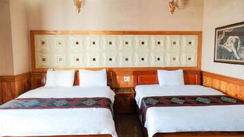 A hotel room with two beds, wooden headboards, and a decorative ceiling panel.