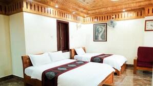 A hotel room with two wooden beds, a red chair, a clock, and a painting on the wall.