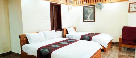 A hotel room with two wooden beds, a red chair, a clock, and a painting on the wall.