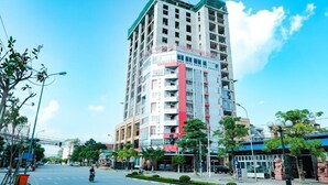 A multi-story building with a modern architectural design, featuring balconies and large windows.