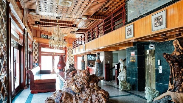 A lobby with a large wooden sculpture, a chandelier, and a high ceiling with intricate woodwork.