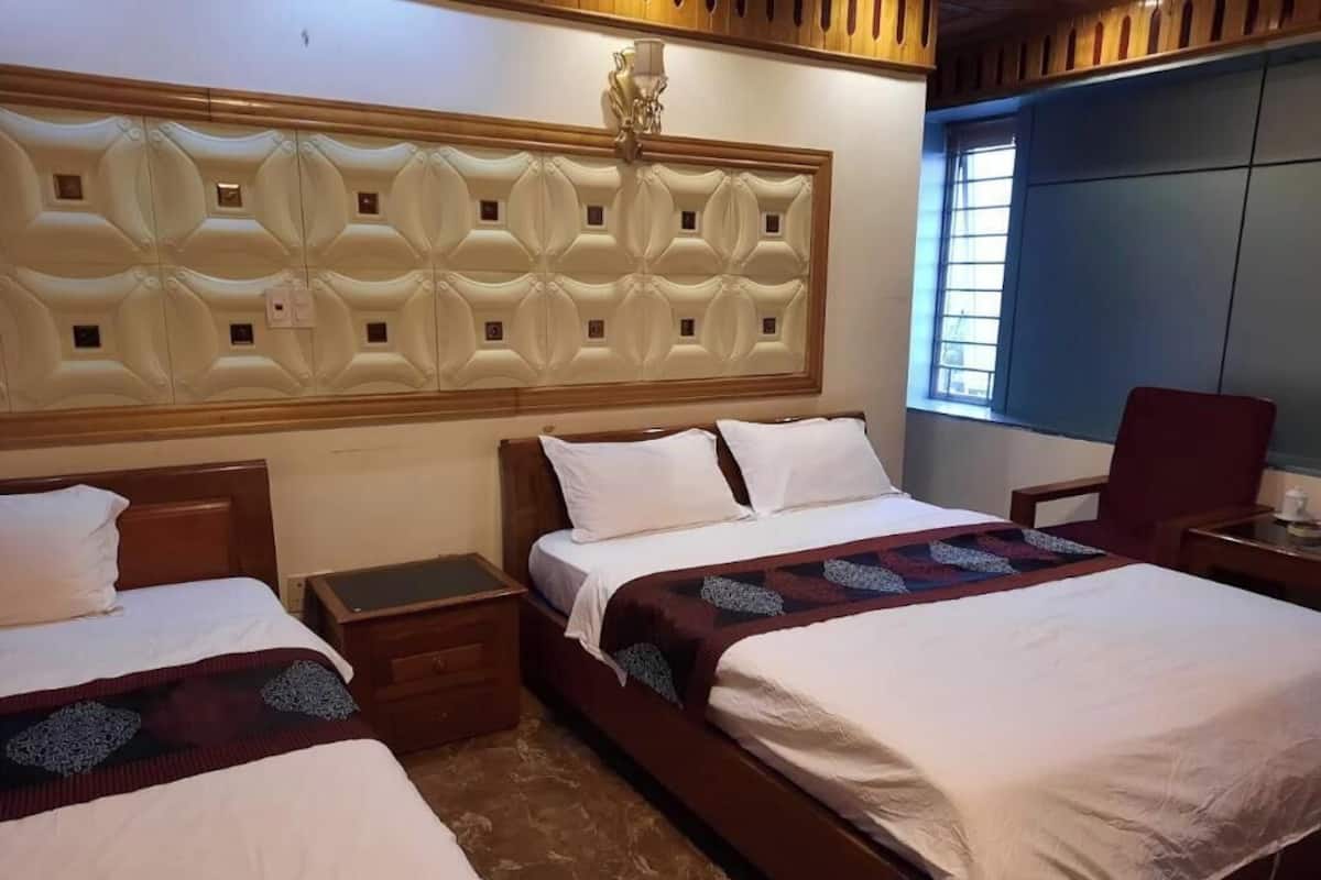 Une chambre d’hôtel avec deux lits, une tête de lit en bois, une table de chevet, un bureau et une chaise.