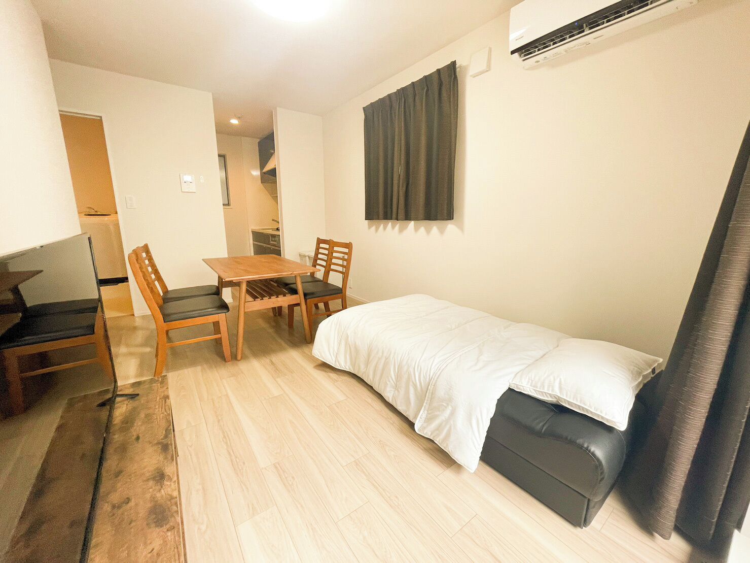 Une pièce de taille modeste, comprenant un lit simple, une petite table, deux chaises et un bureau.