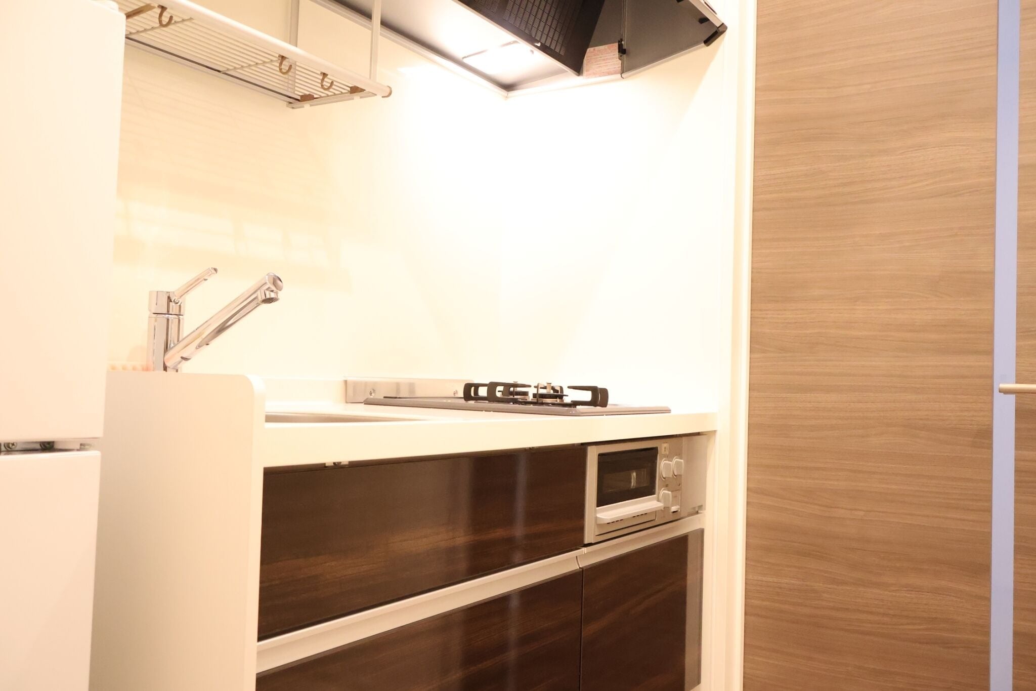 A compact kitchen with a built-in oven, a microwave, and a stainless steel faucet.