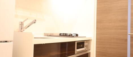 A compact kitchen with a built-in oven, a microwave, and a stainless steel faucet.
