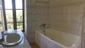 Ein Badezimmer mit Badewanne, Waschbecken und Fenster.