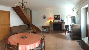 Ein Wohnzimmer mit Kamin, Esstisch und einer Treppe.