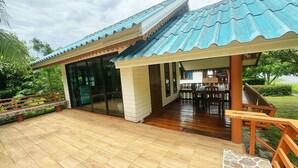 A covered outdoor area with a wooden deck and a dining table. - OYO 75497 Uncle Odd Talay View Resort (Nakhon Nayok)