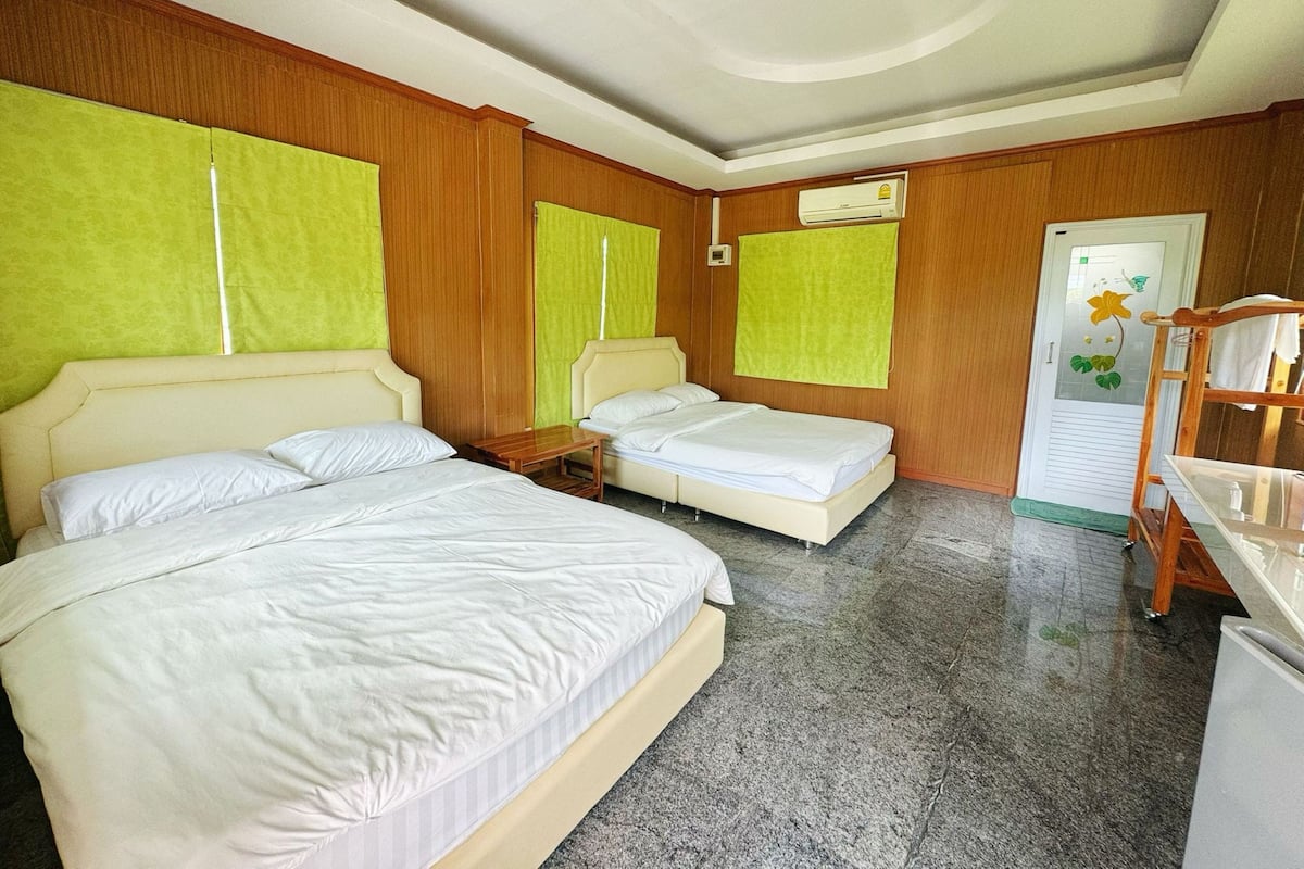 A hotel room with two beds, a wooden wardrobe, a desk, and a bathroom door with a floral design.