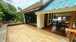 A covered patio area with a wooden floor, a stone border, and a seating area with a table and chairs. - OYO 75497 Uncle Odd Talay View Resort (Nakhon Nayok)