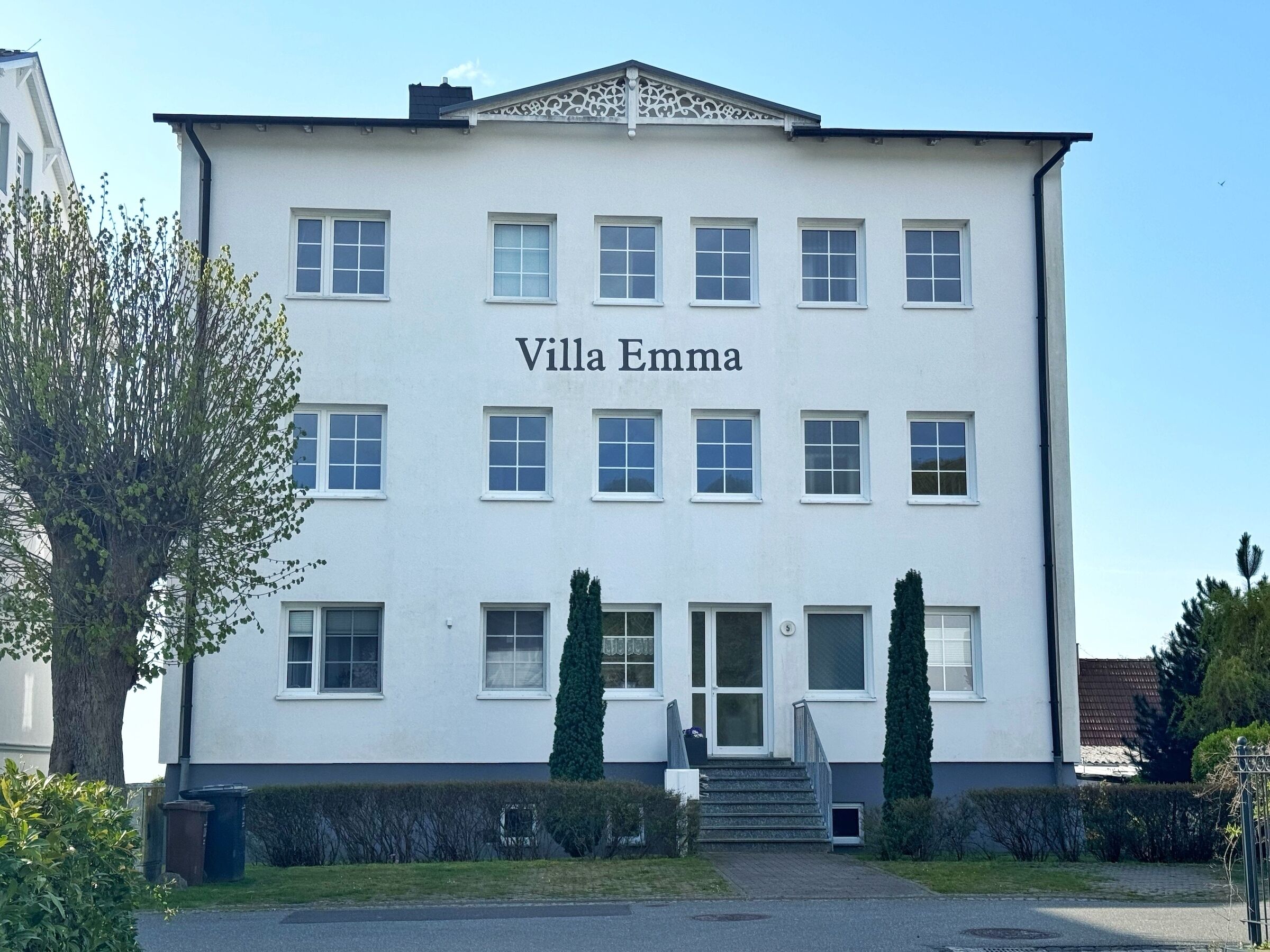 Un bâtiment appelé Villa Emma, doté d’une façade symétrique, de nombreuses fenêtres et d’une entrée centrale avec des marches.