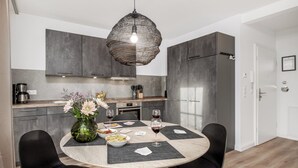 Una cucina moderna con mobili grigi, un tavolo da pranzo rotondo con sedie nere e un lampadario.