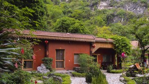 A traditional brick building with a tiled roof, surrounded by lush greenery and a stone pathway. - Tràng An Hometown Homestay (Ninh Binh)