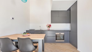 Eine moderne Küche mit grauen Schränken, einem Holztisch und zwei schwarzen Stühlen.
