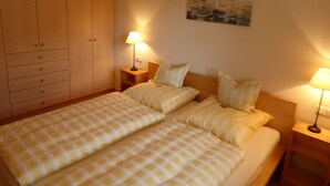 Hotellihuone, jossa on kaksi sänkyä, vaatekaappi, taulu seinällä ja kaksi yöpöytävalaisinta.