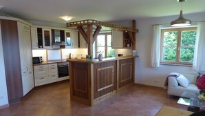Una cucina con mobili in legno, un'isola centrale e una finestra vista verde.