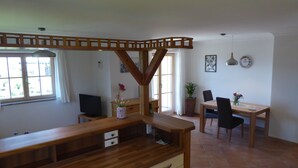 Una cucina moderna con piani in legno e una panca integrata. C'è una zona pranzo con tavolo e sedie, e una pianta in vaso sul davanzale.