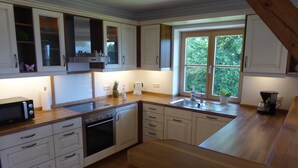Una cucina moderna con mobili bianchi, un piano di lavoro in legno, forno integrato e una finestra che illumina con luce naturale.