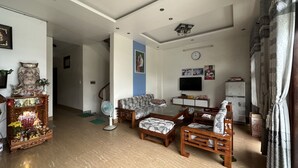 Un salón amplio con un conjunto de sofás, televisión y un altar decorativo.