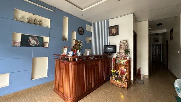 Zona de recepción con mostrador de madera, paredes azules y un televisor.