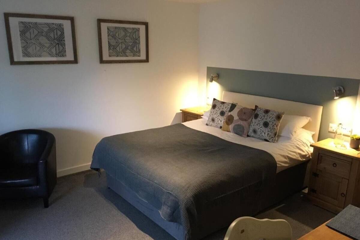 A bedroom with a bed, bedside tables, a chair, and two framed pictures on the wall.