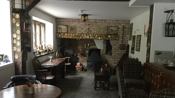 Un pub acogedor con chimenea de ladrillo, muebles de madera y una zona de bar.