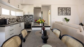 Una cocina moderna con armarios blancos, un salpicadero a cuadros blanco y negro, y un comedor con una mesa dispuesta para cuatro.