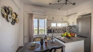 Una cocina moderna con una isla central, un comedor con cuatro sillas y vistas a través de una ventana.