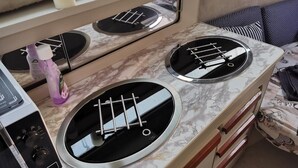 A kitchen with two gas stoves, a sink, and a window above the counter. - Virginia Bed and Boat (Syracuse)