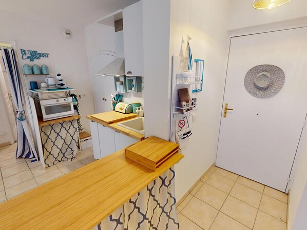 Cuina compacta amb forn integrat, una aixeta i taula de fusta.