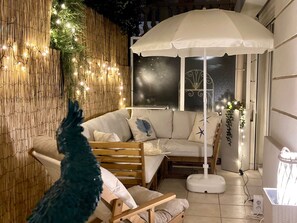 A cozy room with a sofa, a standing fan, and a decorative umbrella.