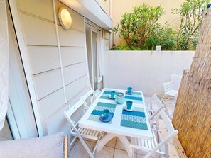 A white outdoor table set with blue tablecloths and chairs, a wicker chair, and a bamboo fence.
