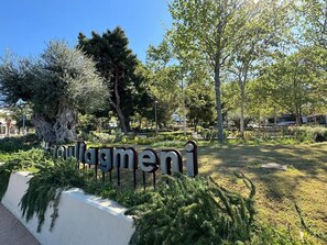 A sign with the name 'Yolagmen' in a park-like setting with trees and greenery.